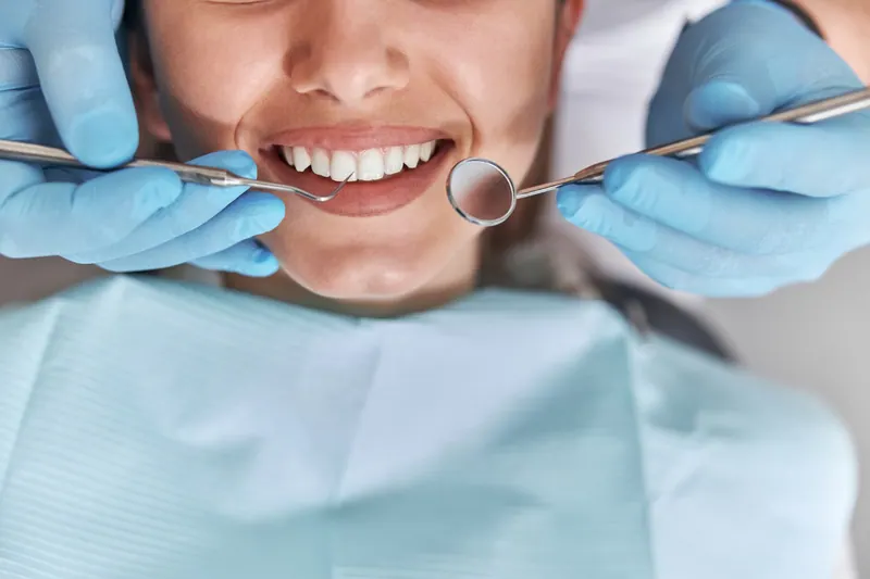 Dental professional examining a patient’s teeth with a mirror